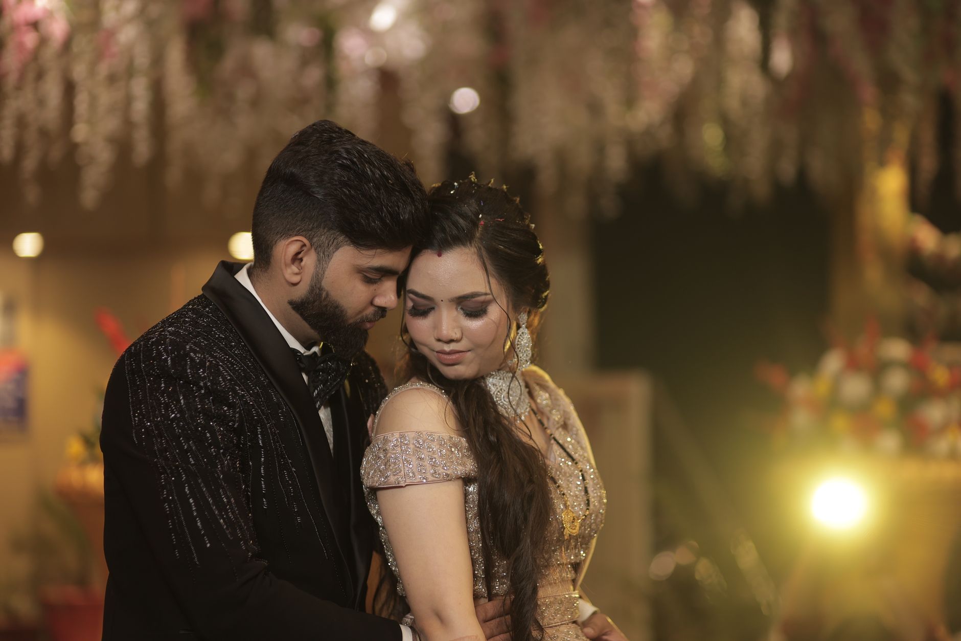 A couple embraces tenderly at a beautifully decorated evening event indoors.
