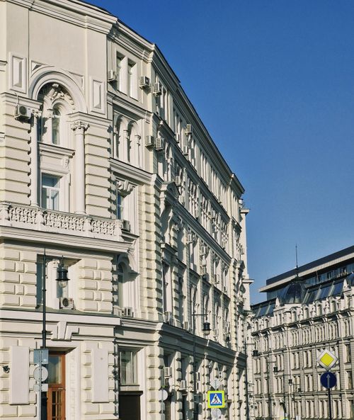 Free Elegant white classical building facade with architectural details under a clear blue sky. Stock Photo