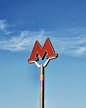 Iconic red metro sign standing tall against a blue sky, symbolizing urban transit.