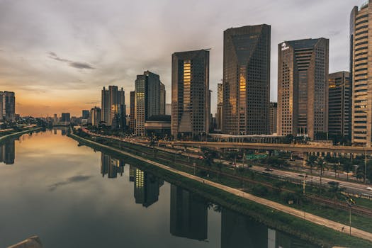 黄昏时分，现代摩天大楼的天际线倒映在河中，构成一幅宁静的城市景观