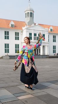 Woman in vibrant batik attire performs traditional dance outdoors in Jakarta's historic city square. - Fotografer Sidoarjo