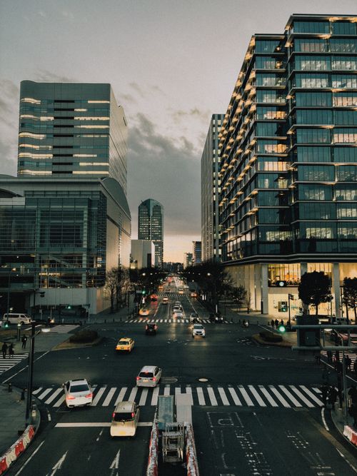 Free A bustling street in Yokohama, Japan, framed by modern high-rise buildings at twilight. Stock Photo