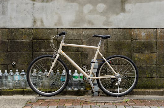 A classic bicycle parked against a weathered wall in Itabashi, Tokyo, Japan, with plastic bottles lining the base.