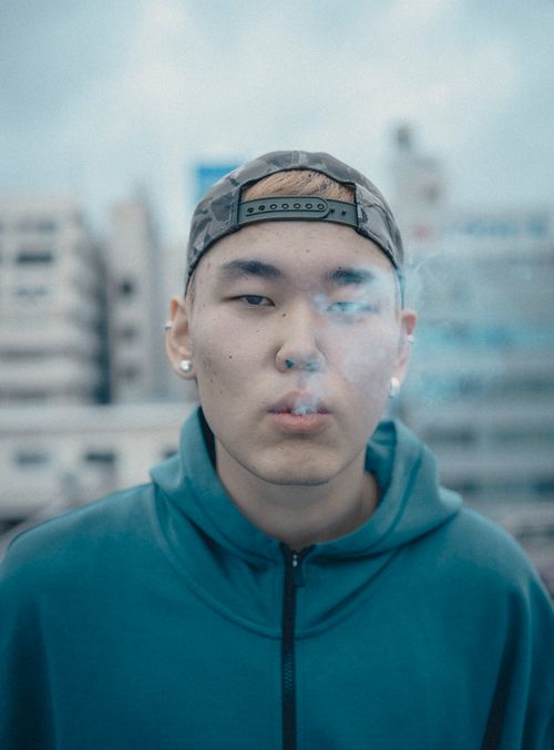 Free Portrait of a young man smoking in the urban backdrop of Shinjuku, Tokyo. Stock Photo