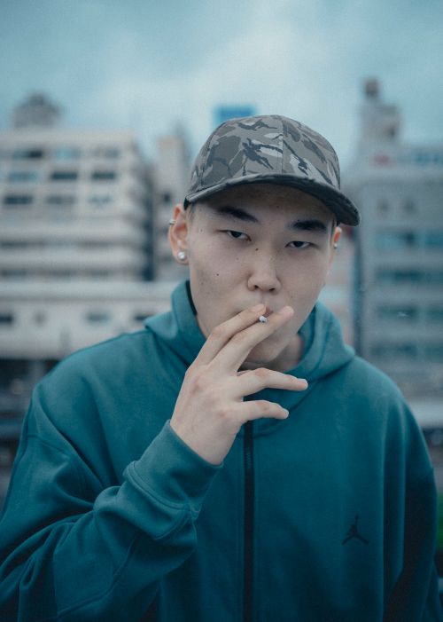Free Portrait of a young man smoking in Shinjuku, Tokyo, with urban cityscape in the background. Stock Photo