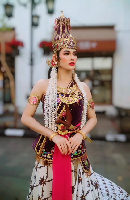 Woman in traditional Indonesian attire posing outdoors, showcasing cultural elegance.