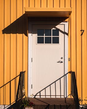 Brightly colored yellow building facade featuring a white door with window panes.