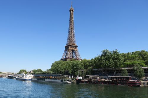 Free The iconic Eiffel Tower seen from across the Seine River in Paris under a clear blue sky. Stock Photo