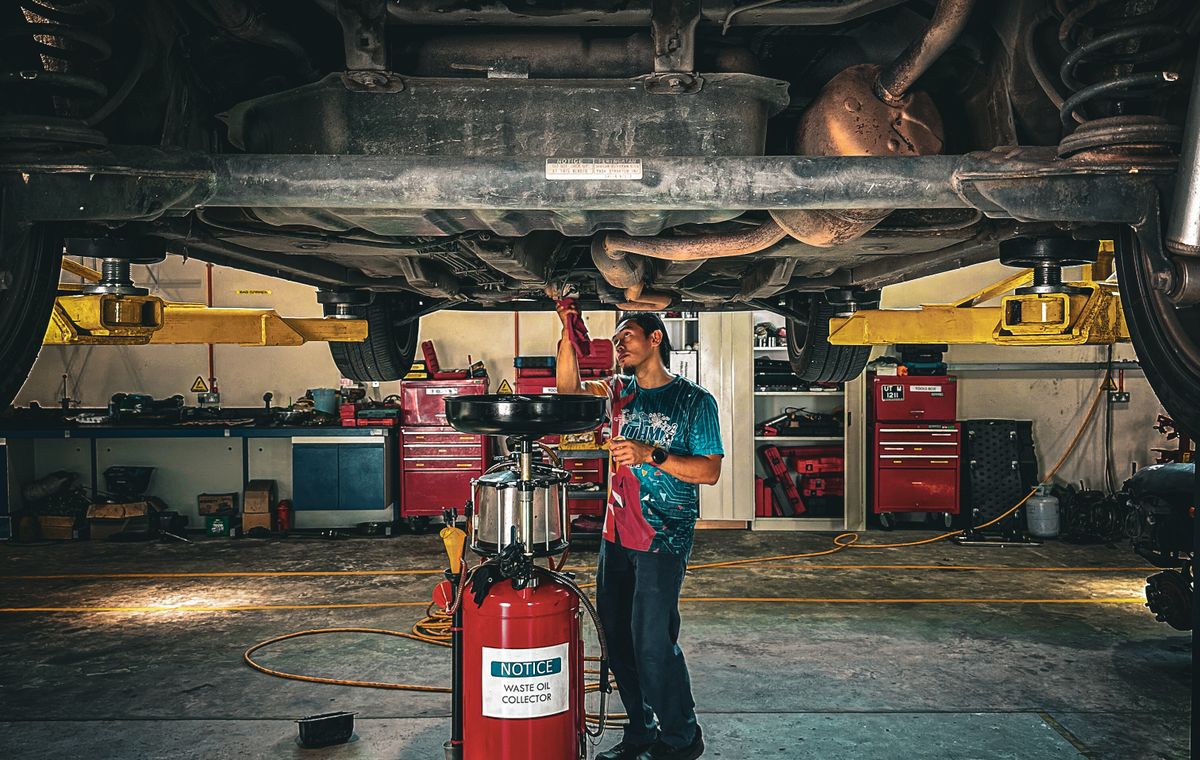 Mechanic inspecting the underside of a vehicle in a repair shop