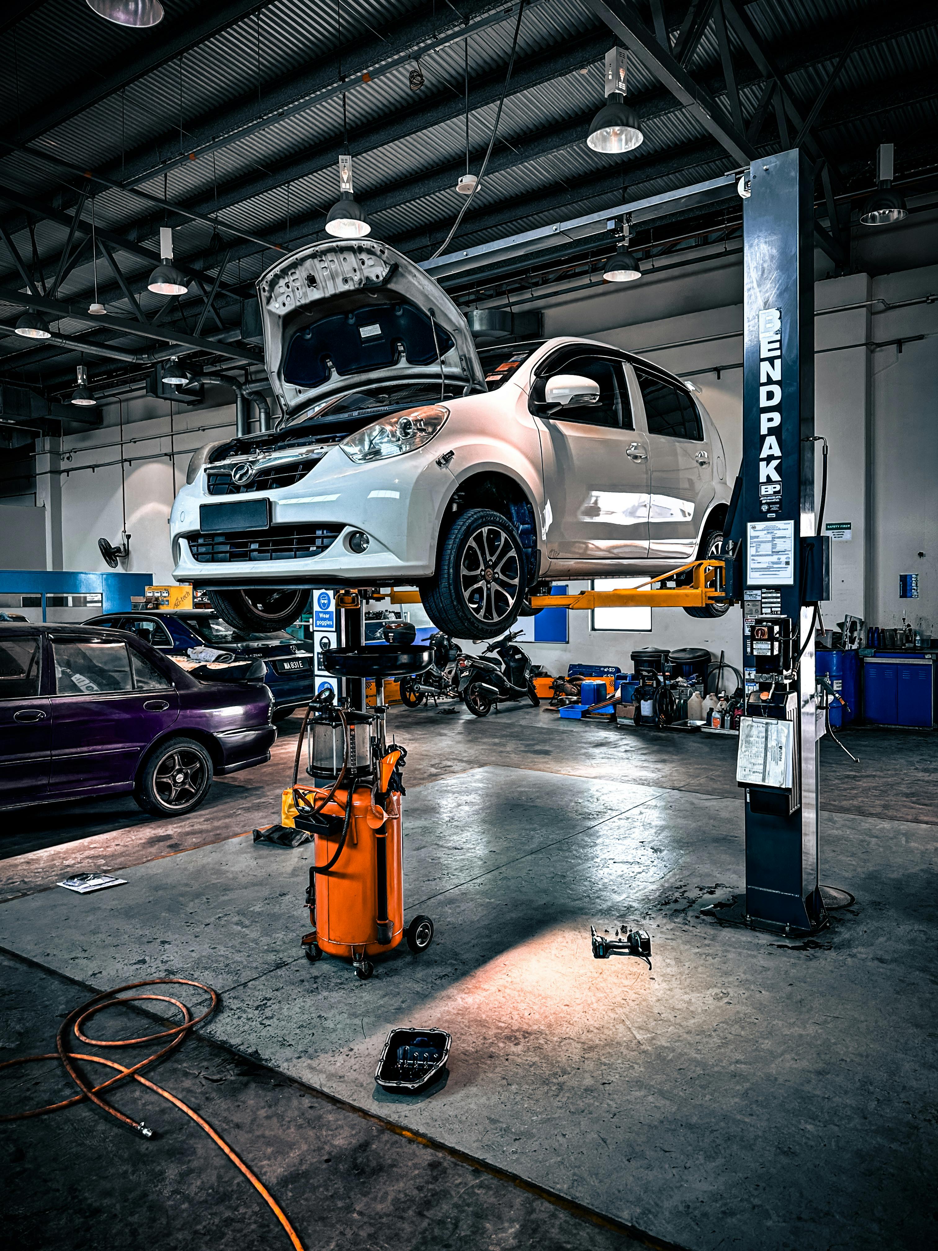 Officina moderna con auto sollevata su ponte idraulico e attrezzi
