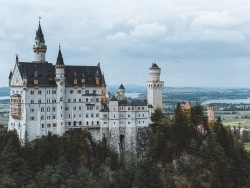 Free A stunning view of Neuschwanstein Castle surrounded by lush greenery in Schwangau, Bavaria. Stock Photo