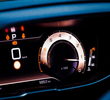 Detailed view of a car dashboard, featuring speedometer and warning lights.