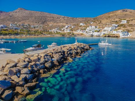 Stunning view of a Greek island harbor with boats and a vibrant coastline under a clear blue sky.