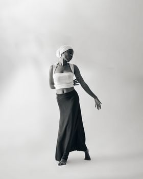 A poised woman in a dance pose in monochrome with graceful arm movement.