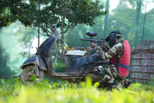 Person in camouflage gear playing paintball outdoors in Bengaluru, Karnataka.