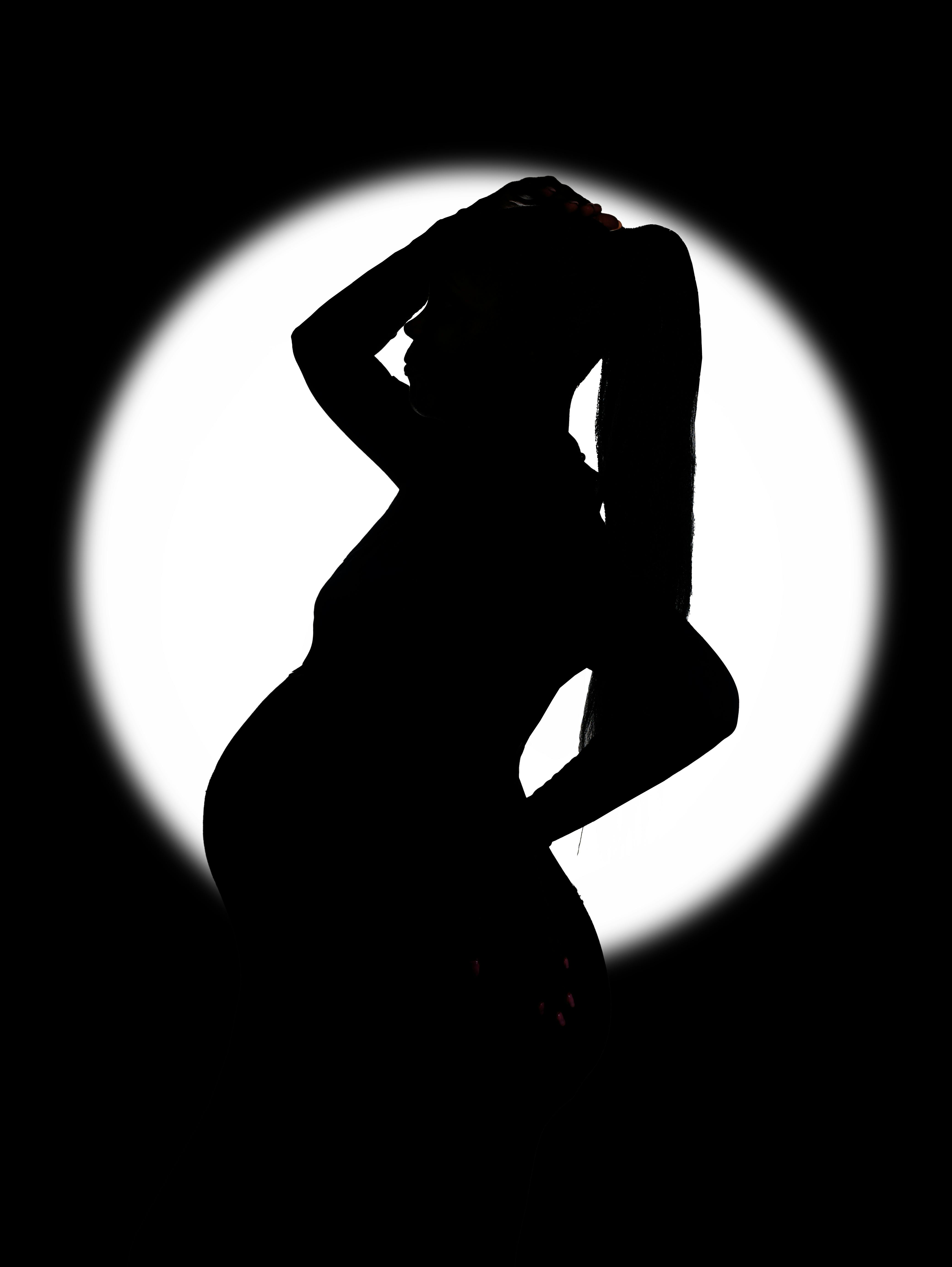 Gratis Silhouette artistica di una donna incinta in posa di profilo su uno sfondo luminoso. Foto a disposizione