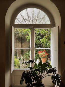 A picturesque view of a lush garden through an arched window featuring potted plants.