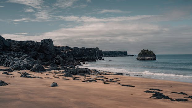 Scenic view of rocky coastline in Snæfellsbær, Iceland with overcast sky.