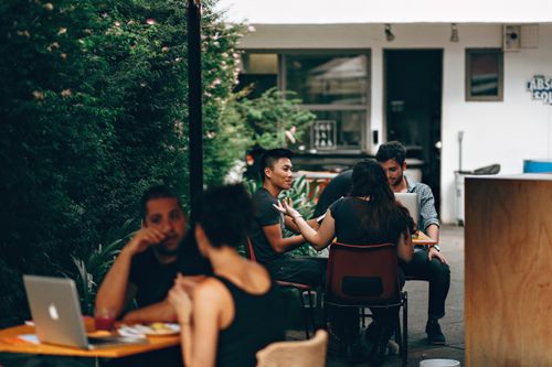 Free Young adults in a relaxed outdoor café setting in Belo Horizonte, engaging in conversation and work. Stock Photo