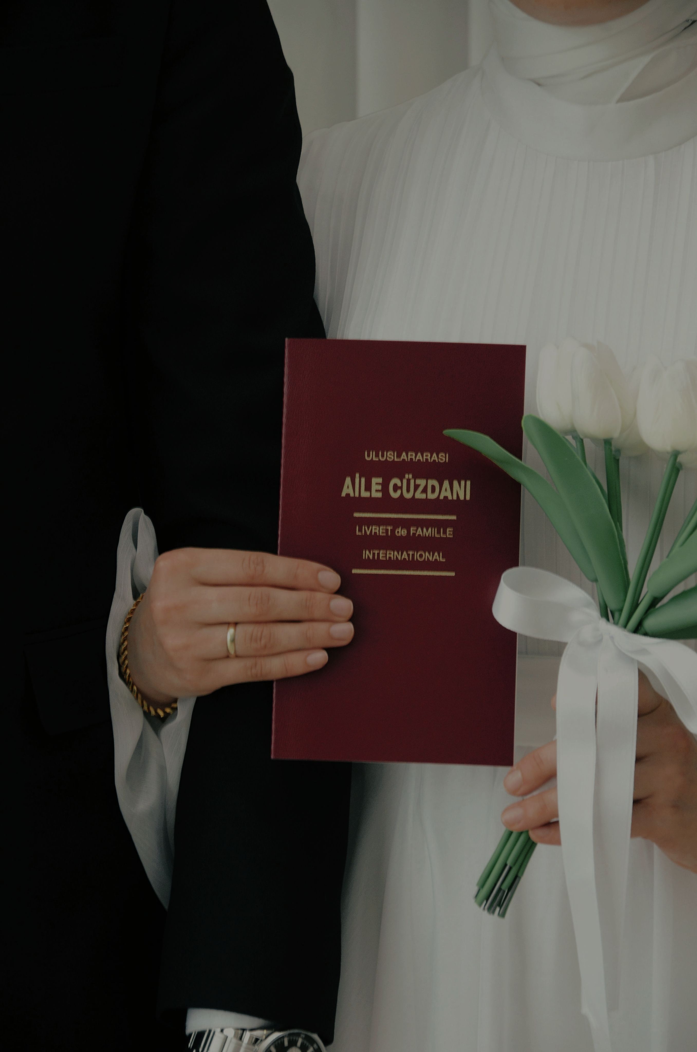 A close-up of a couple holding a marriage book and tulips, symbolizing a wedding ceremony.