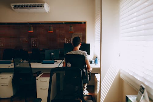 Person in Gray Shirt Sitting on Computer Chair