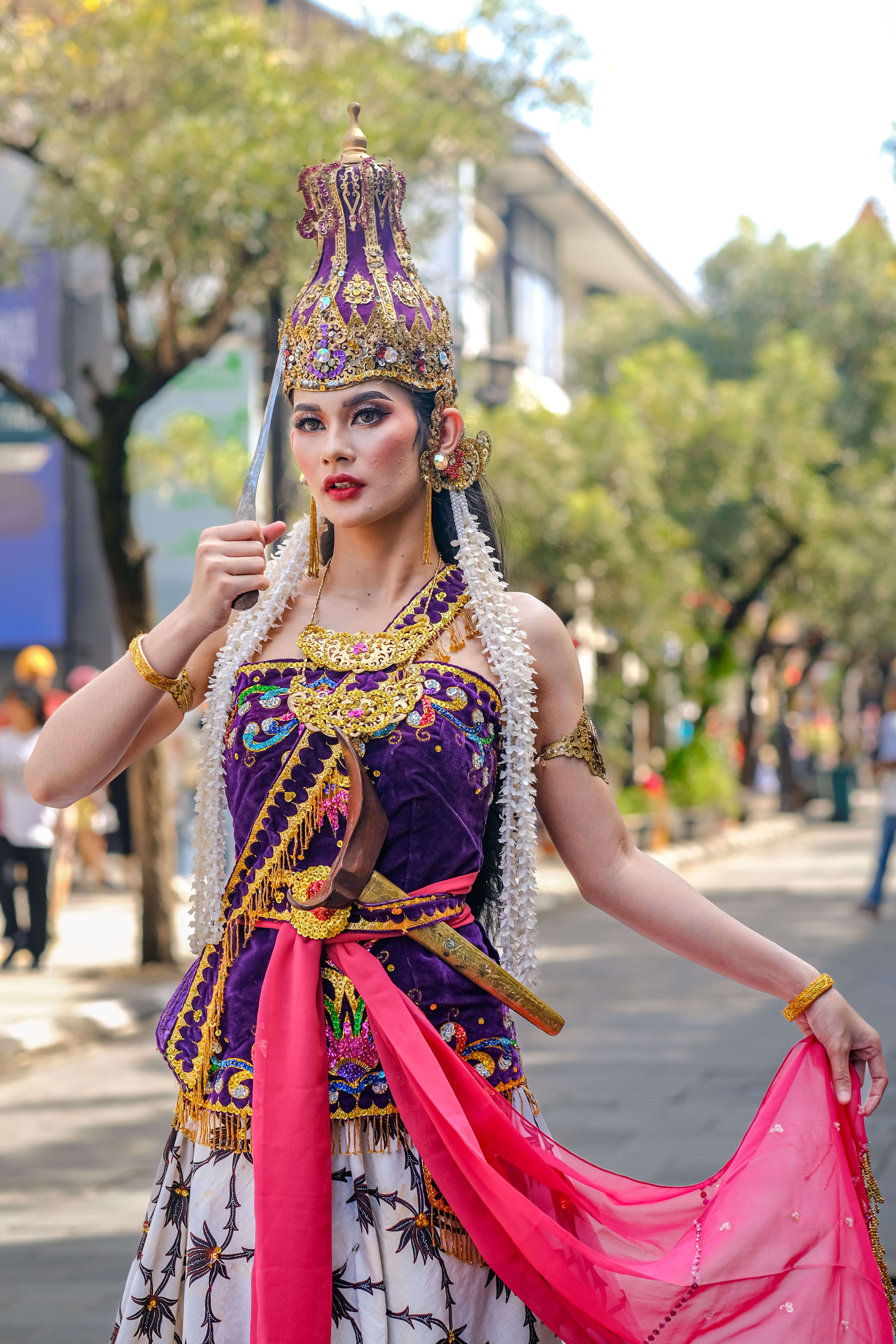 A woman in vibrant traditional Indonesian attire at a street cultural event in West Java.