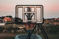 Outdoor basketball hoop with colorful net against a scenic sunset in Denmark.
