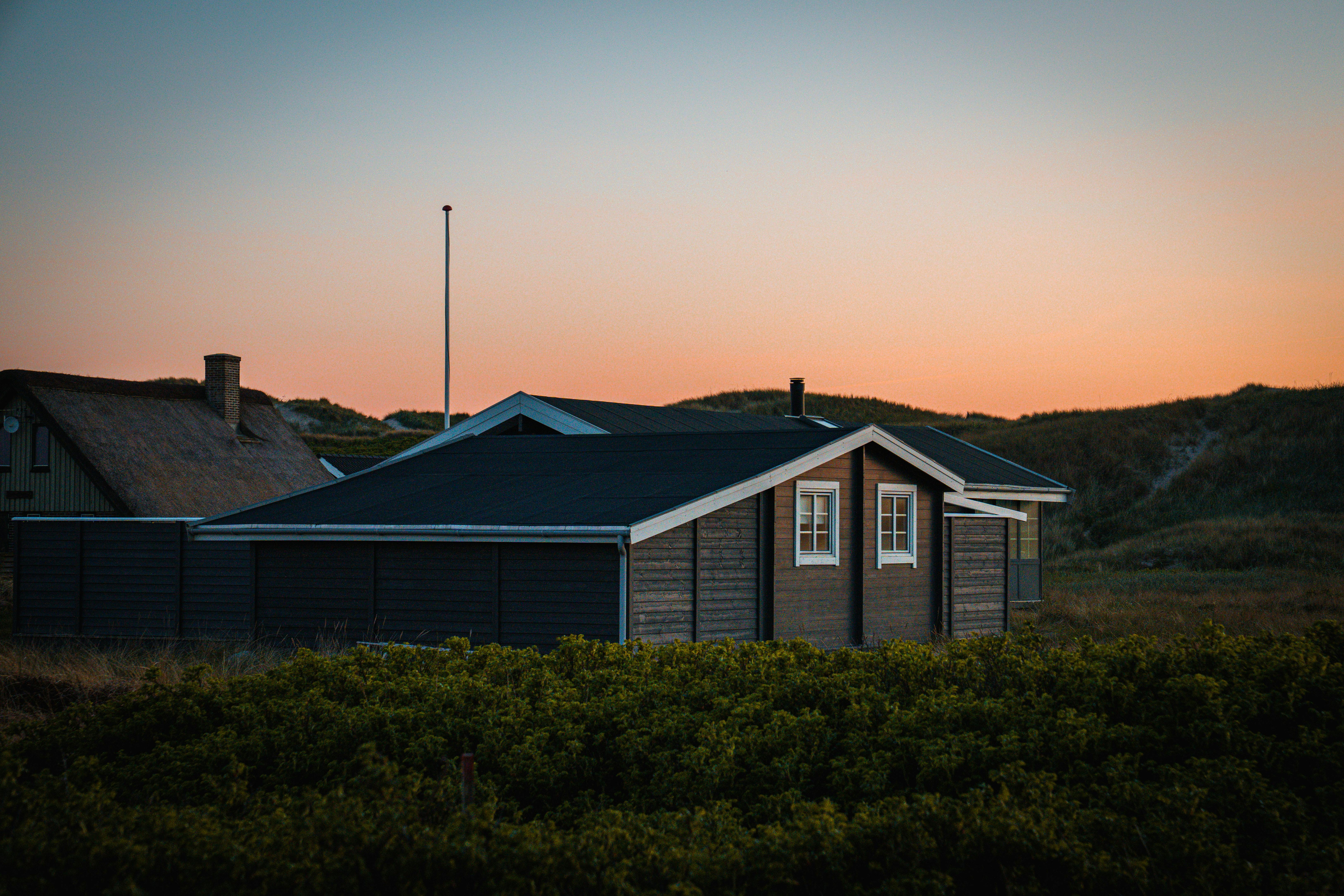 Vue panoramique d'un charmant cottage danois niché au milieu des dunes au coucher du soleil.