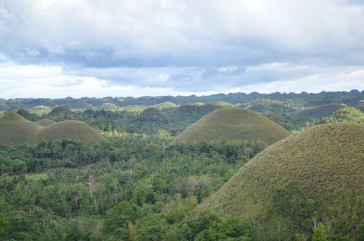 A breathtaking view of the Chocolate Hills in Bohol, with lush greenery and dramatic skies.