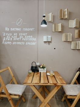 Rustic cafe setting with wooden furniture and open books on the wall.