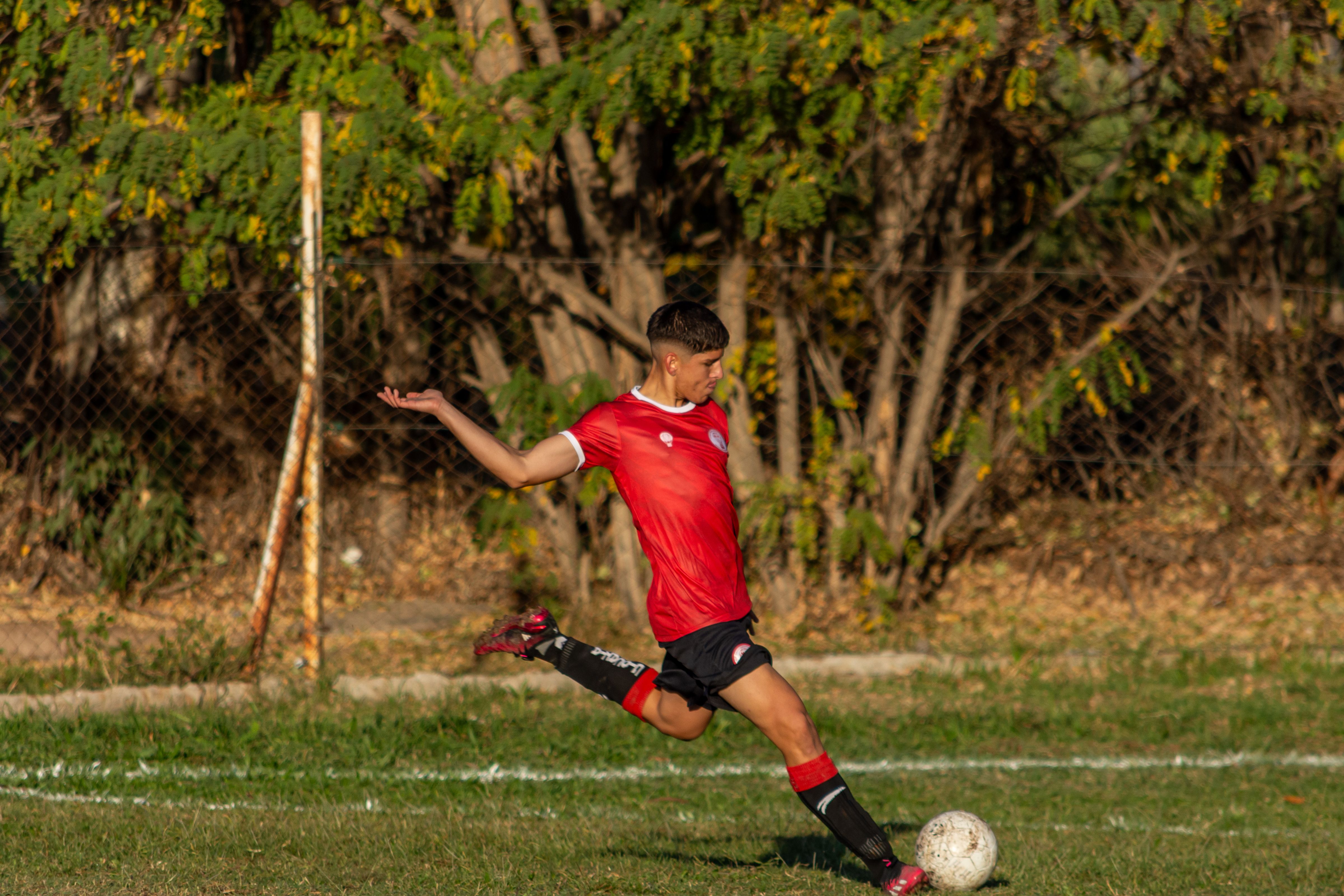 Young Male Soccer Player Kicking Ball Outdoors · Free Stock Photo