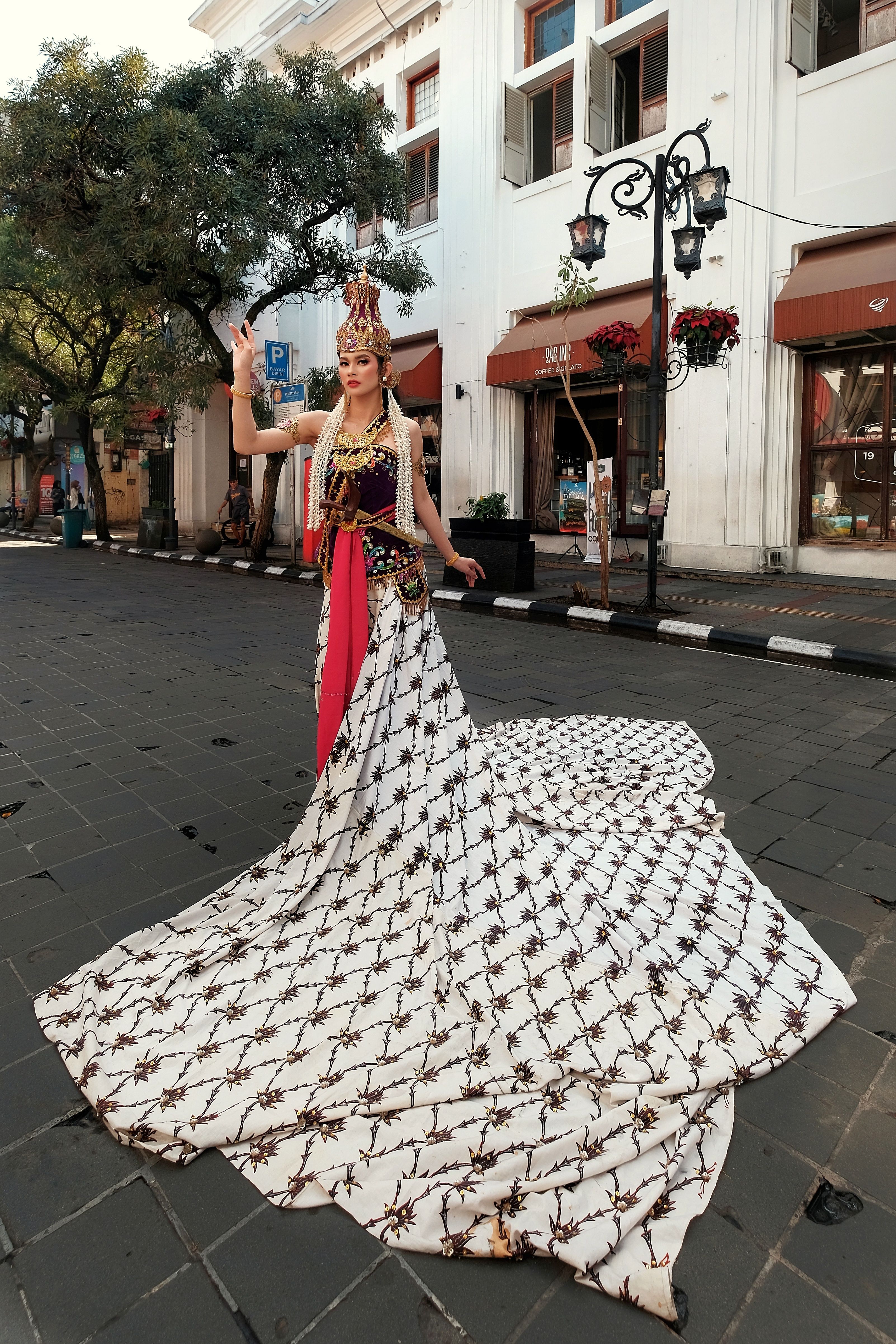 Woman in intricate traditional attire poses on a street in West Java, Indonesia.