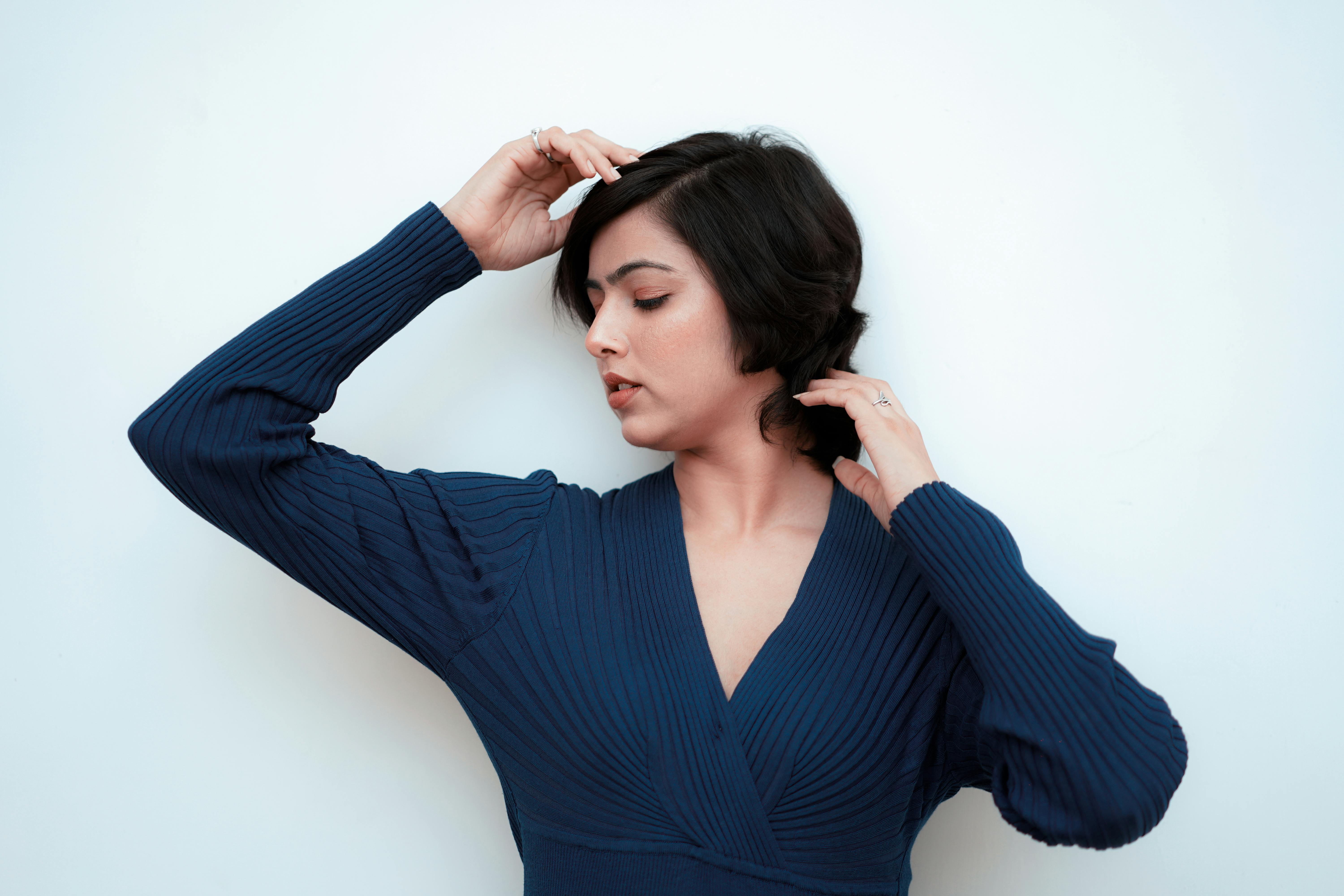 Serene portrait of a woman in a blue dress posing gracefully against white background.
