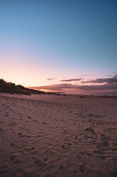 Tranquil beach sunset in Heringsdorf, Germany with footprints in sand and vibrant sky.
