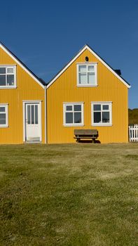 Picturesque yellow house under blue skies in Iceland's scenic landscape.