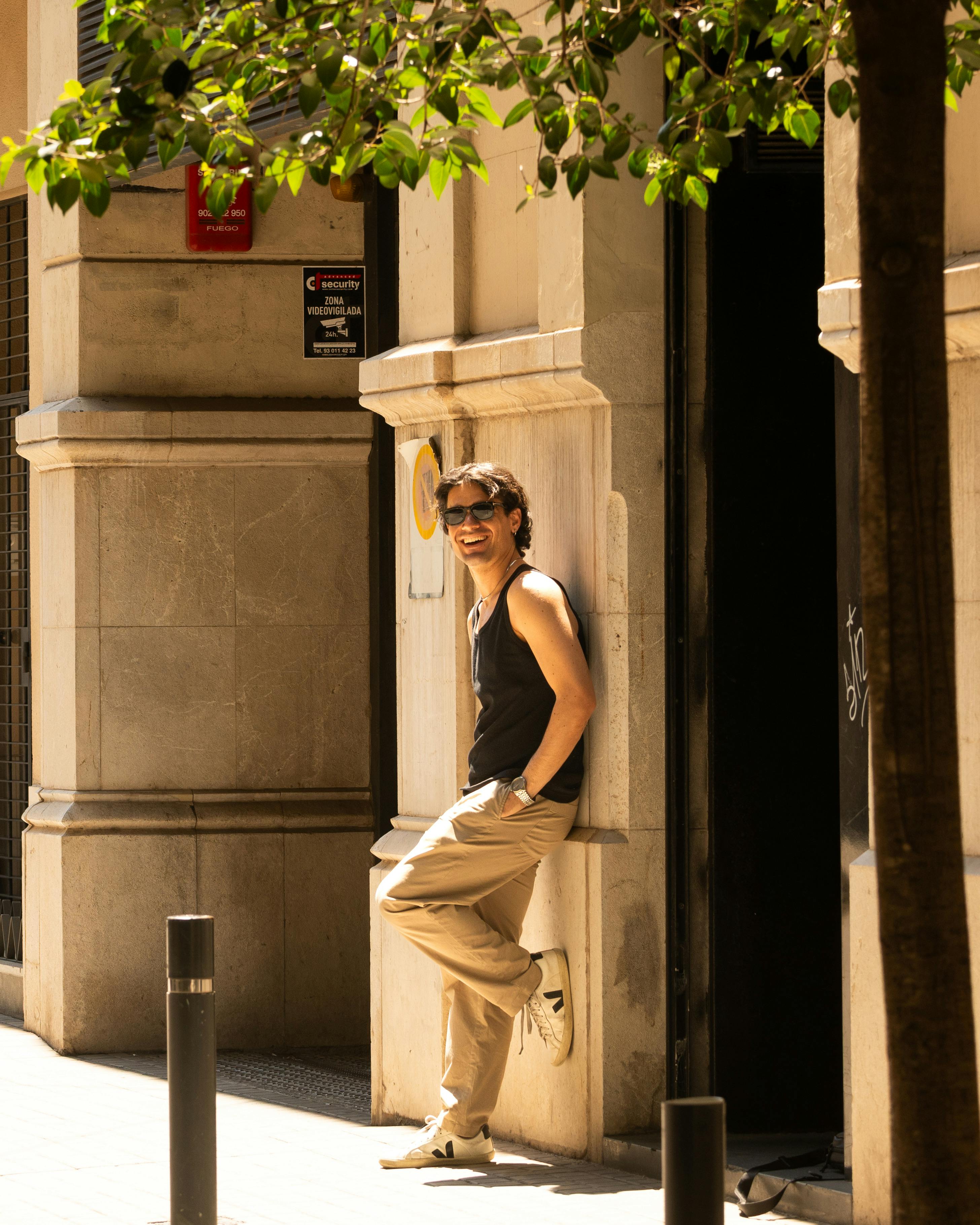 Man leaning against building in sunny Barcelona street scene.