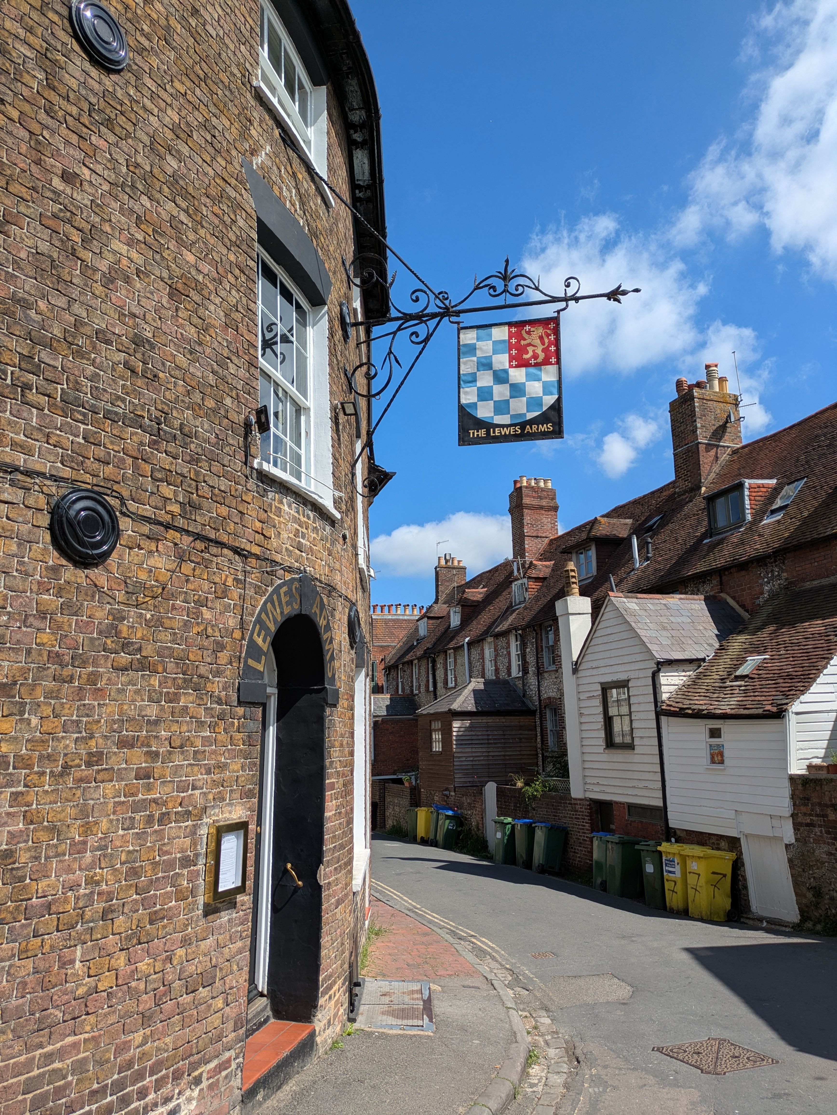 Charming view of a historical street in Lewes featuring The Lewes Arms pub sign and old architecture.