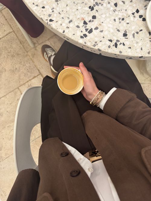 Free Overhead view of a person holding coffee cup, wearing brown suit, casual indoor setting. Stock Photo