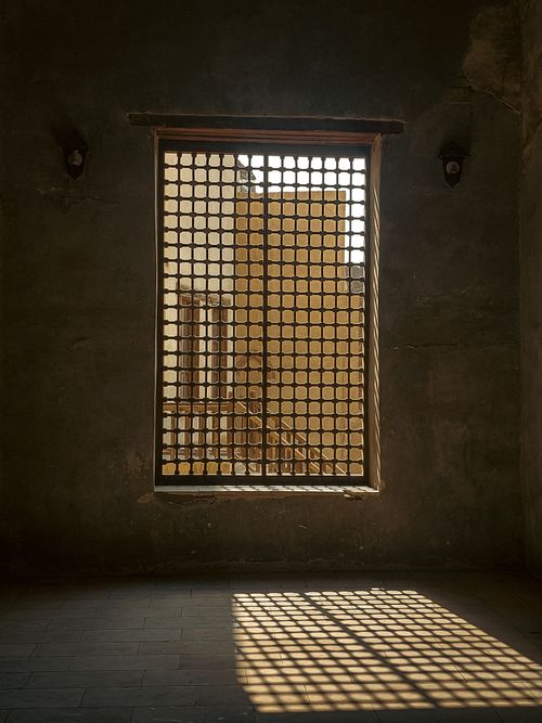 Free Sunlit shadows from a lattice window create a moody interior ambiance. Stock Photo