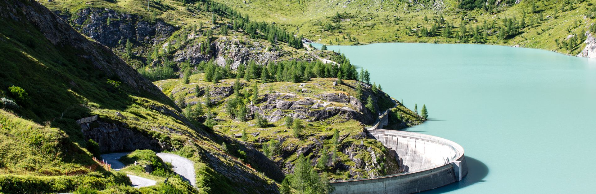 Scenic view of an alpine reservoir surrounded by lush green mountains in Korutany, Austria.