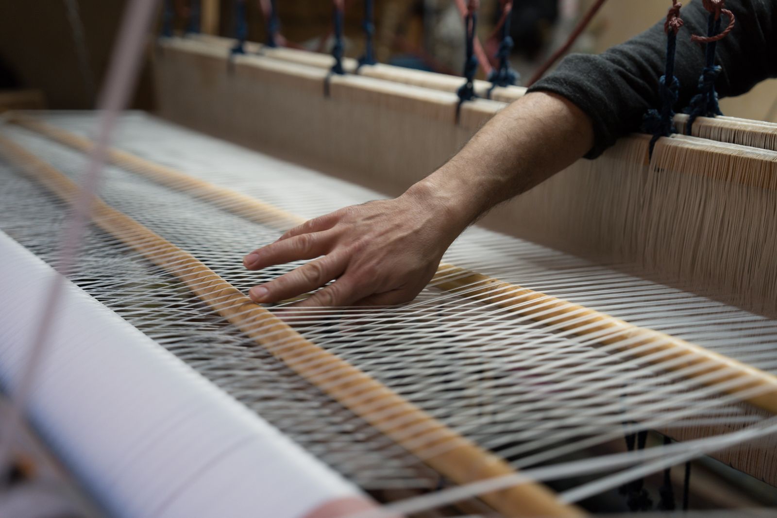 A hand working on a loom