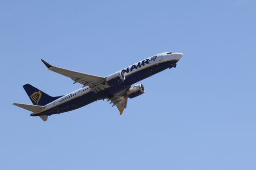 Free A Ryanair commercial airplane in flight, set against a vibrant blue sky, showcasing aviation in action. Stock Photo