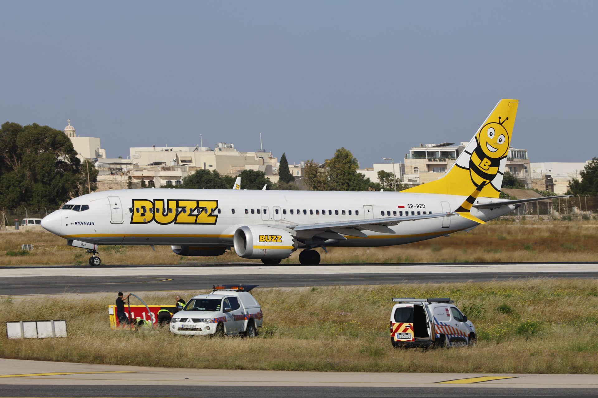 Buzz airline plane on runway, featuring bright yellow and bee logo design, ready for takeoff.