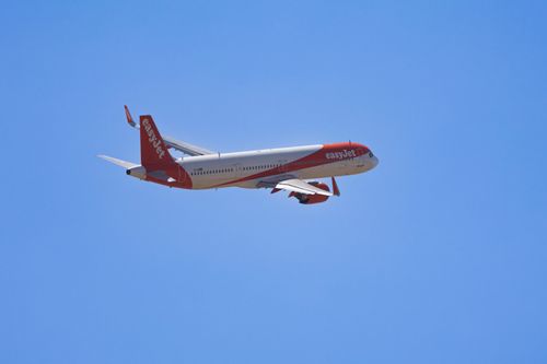 Free An airplane with red and white colors soaring through a bright blue sky, no visible landmarks. Stock Photo