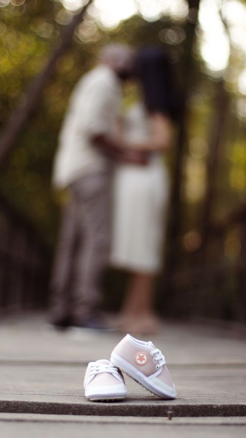 Free Blurred couple in nature with baby shoes symbolizing pregnancy and new beginnings. Stock Photo