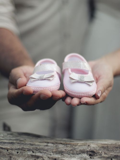 Free Close-up of parents holding delicate pink baby shoes, symbolizing an upcoming arrival. Stock Photo