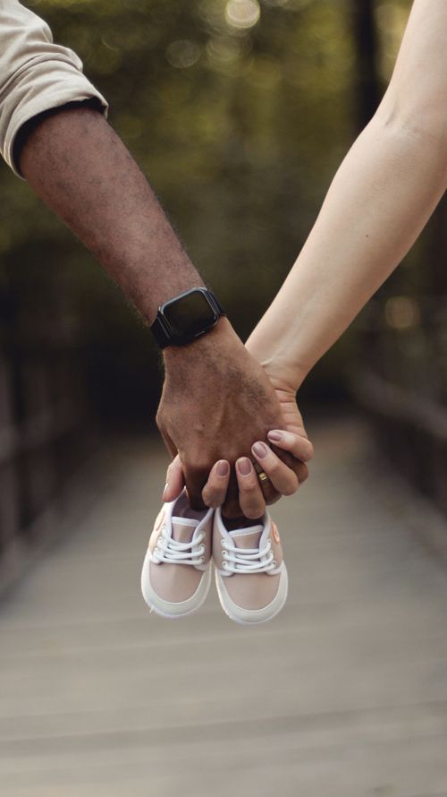Free Close-up of couple holding baby shoes, symbolizing pregnancy announcement. Stock Photo