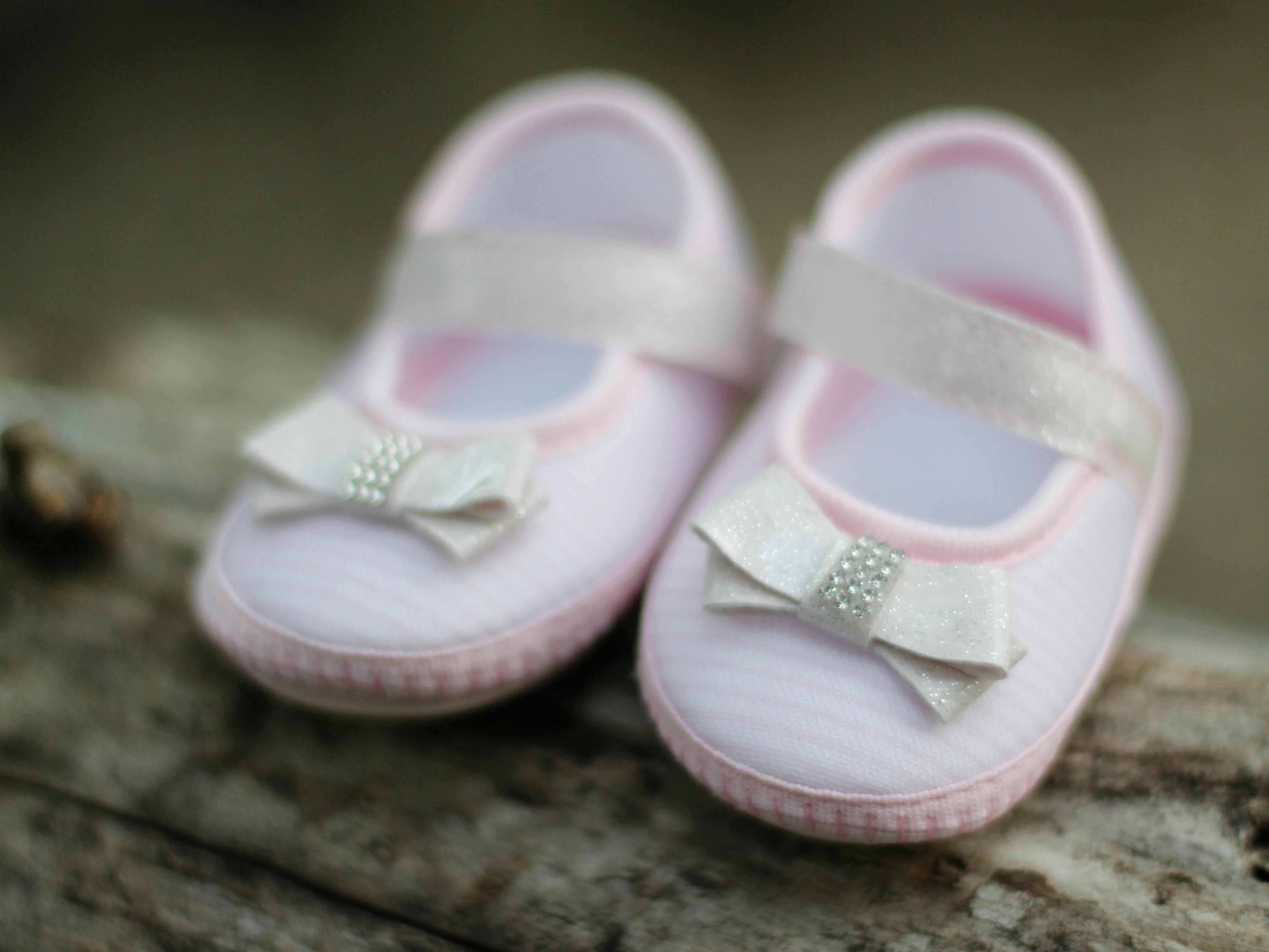 Close-up of adorable pink baby shoes with decorative bows, perfect for expecting parents.