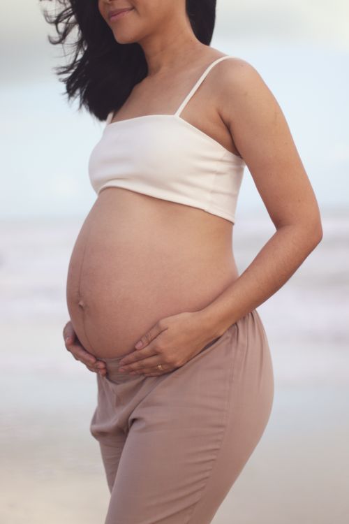 Free A serene image of a pregnant woman on the beach, celebrating the joy of impending motherhood. Stock Photo