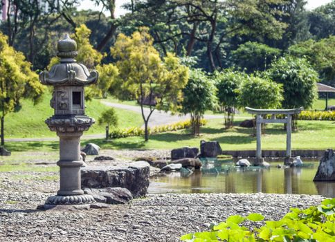 Tranquil view of a Japanese garden featuring a stone lantern and pond.